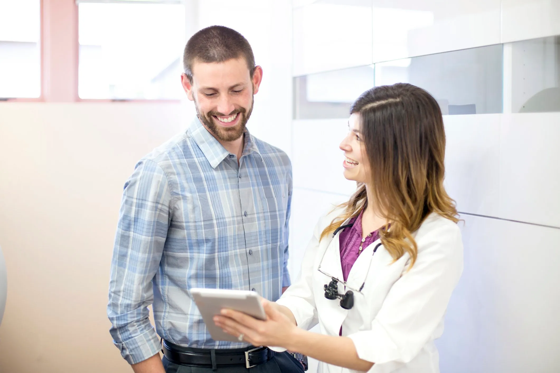 Sales representative and dentist looking at a tablet together in an office setting.
